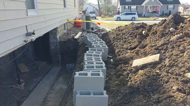 Steel pier installation process at a residential foundation showing bracket placement and pier driving by JLB