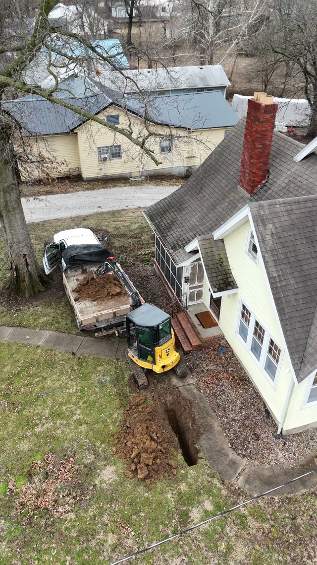 Drone footage of a JLB drainage installation showing French drain trenches, gravel beds, and water management grading