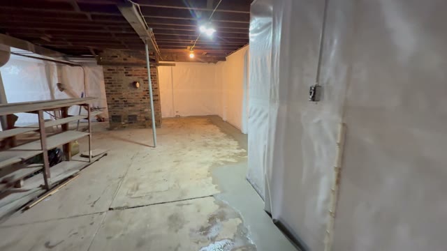 Completed basement waterproofing system with drain tile, sump pump, and sealed walls ready for use